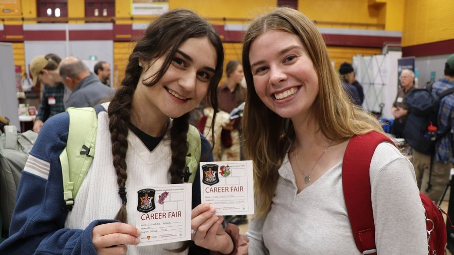 Two smiling people hold up cards reading Career Fair