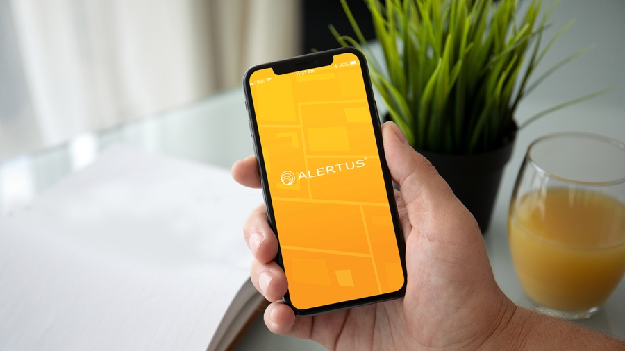 A person holds a phone with the Alertus app open.