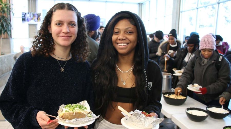 Two students stand and smile